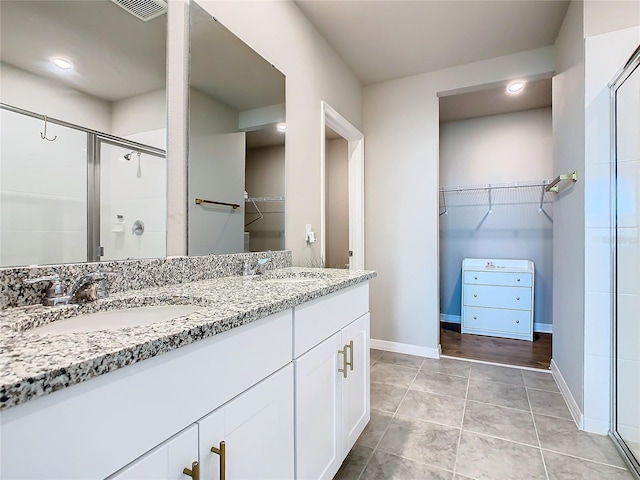 bathroom featuring tile patterned floors, vanity, and a shower with shower door