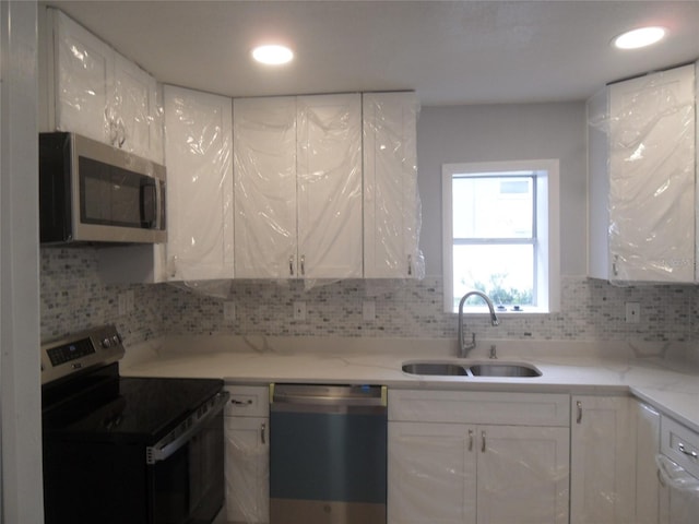 kitchen featuring backsplash, sink, white cabinets, and appliances with stainless steel finishes