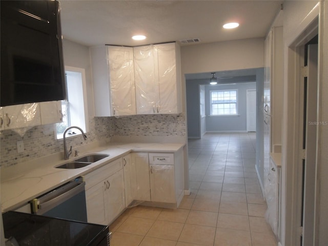 kitchen with dishwasher, stove, backsplash, sink, and white cabinetry