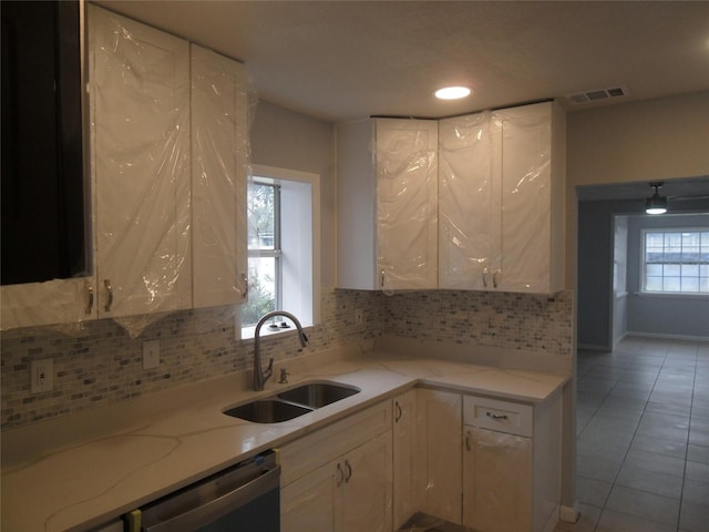 kitchen featuring backsplash, sink, light tile patterned floors, and stainless steel dishwasher