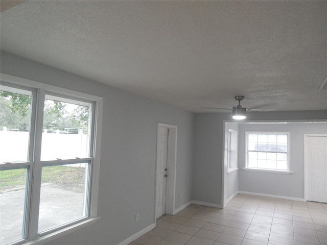 tiled empty room with a textured ceiling, a wealth of natural light, and ceiling fan