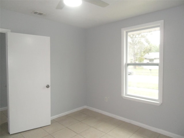 tiled empty room featuring plenty of natural light and ceiling fan