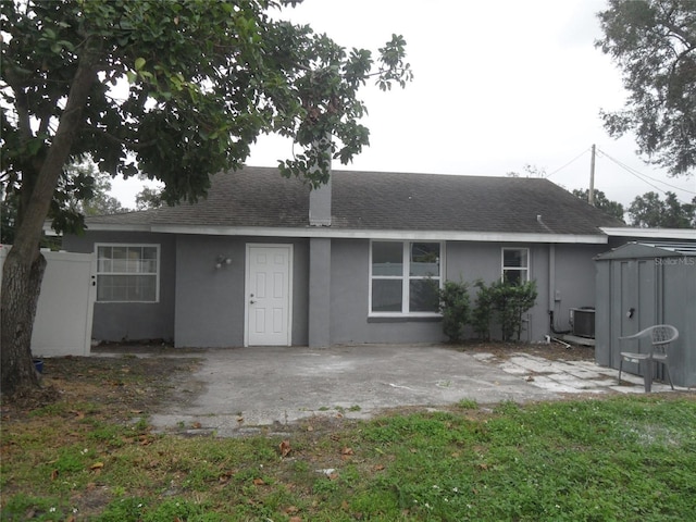 back of property with central AC and a patio area