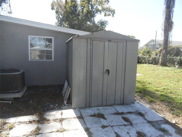 view of outdoor structure with central AC and a yard