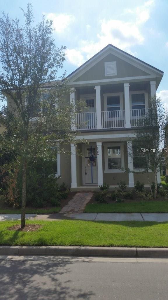 greek revival inspired property with a front yard and a balcony