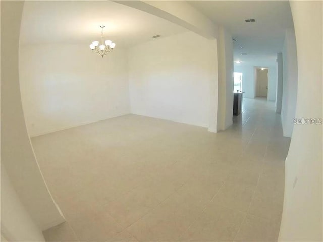 tiled empty room featuring a notable chandelier