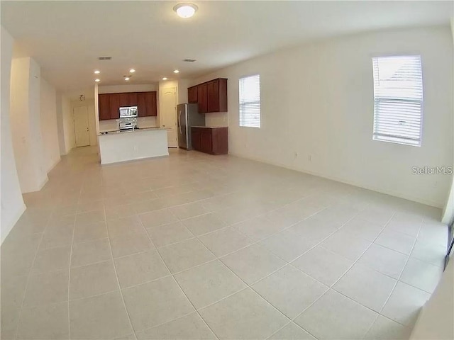 unfurnished living room with light tile patterned floors and plenty of natural light