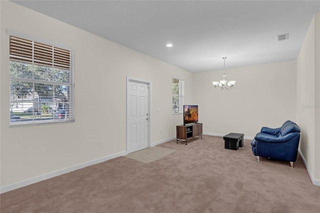 unfurnished room featuring a chandelier, light colored carpet, and a healthy amount of sunlight