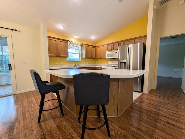 kitchen featuring lofted ceiling, dark hardwood / wood-style floors, a kitchen island, and white appliances