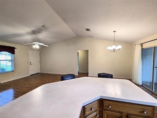 kitchen featuring hanging light fixtures, dark wood-type flooring, a textured ceiling, vaulted ceiling, and ceiling fan with notable chandelier