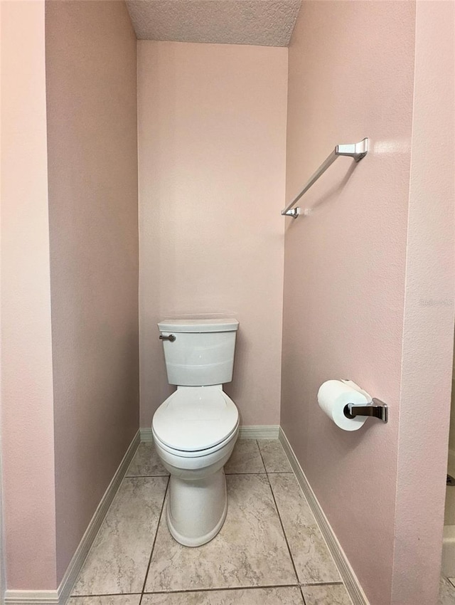 bathroom with tile patterned floors, a textured ceiling, and toilet