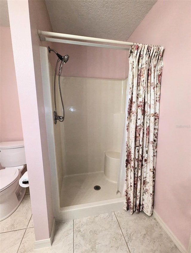 bathroom featuring tile patterned floors, toilet, a textured ceiling, and walk in shower