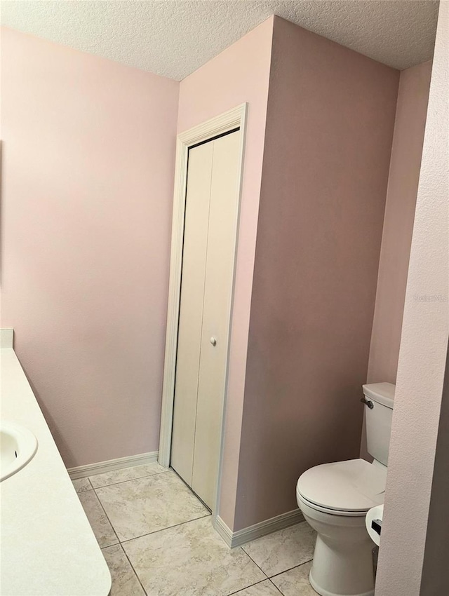 bathroom with tile patterned flooring, vanity, a textured ceiling, and toilet