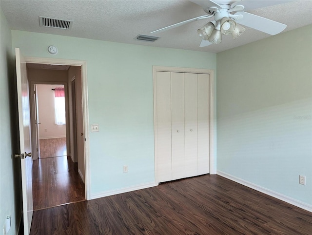 unfurnished bedroom with a closet, ceiling fan, dark hardwood / wood-style flooring, and a textured ceiling