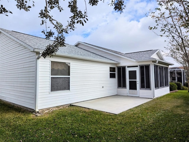 rear view of house featuring a lawn, a sunroom, and a patio