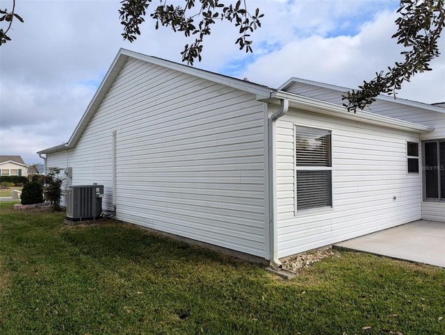 view of side of property with a patio area, central air condition unit, and a yard