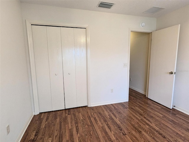 unfurnished bedroom featuring a closet and dark hardwood / wood-style floors