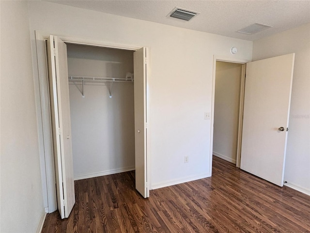 unfurnished bedroom featuring dark hardwood / wood-style flooring, a textured ceiling, and a closet