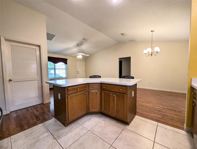 kitchen with decorative light fixtures, a center island, light wood-type flooring, and vaulted ceiling