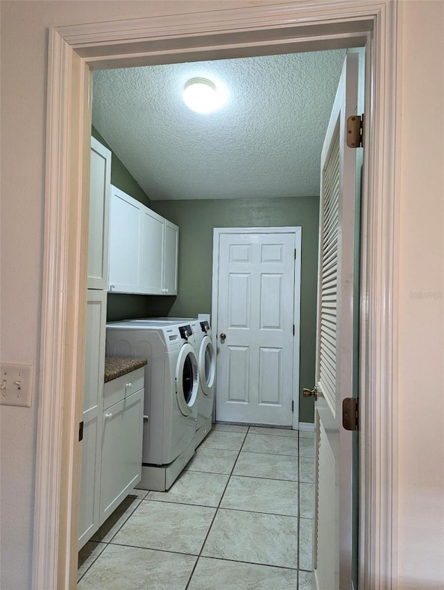 washroom with washer and clothes dryer, cabinets, light tile patterned floors, and a textured ceiling