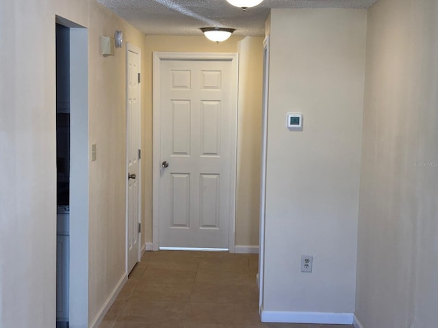 corridor featuring dark tile patterned floors and a textured ceiling