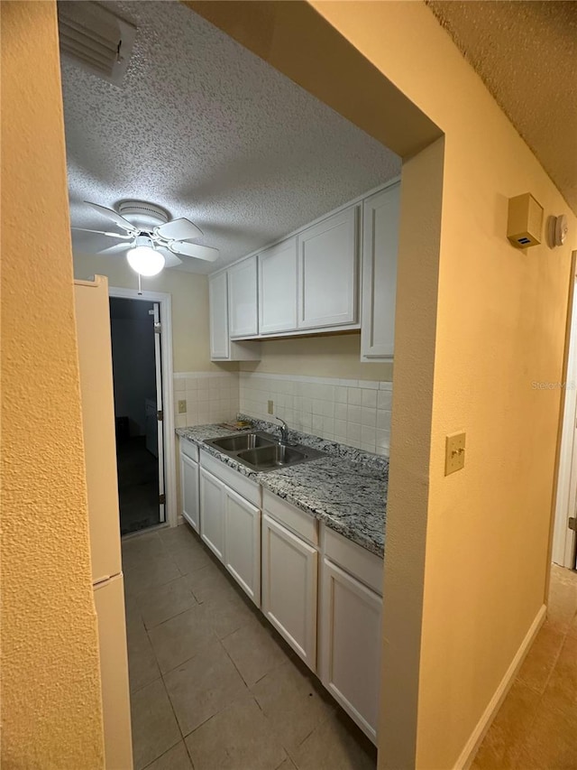 kitchen featuring backsplash, light stone counters, sink, and white cabinets