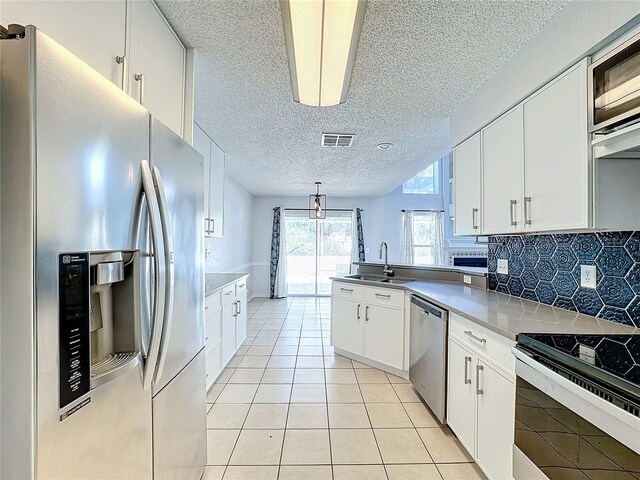 kitchen featuring backsplash, stainless steel appliances, sink, white cabinetry, and light tile patterned flooring