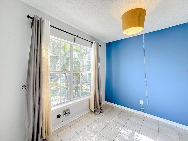 spare room featuring light tile patterned flooring and a textured ceiling