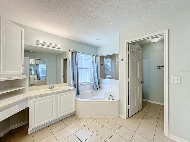 bathroom featuring tile patterned flooring, vanity, a textured ceiling, and tiled tub