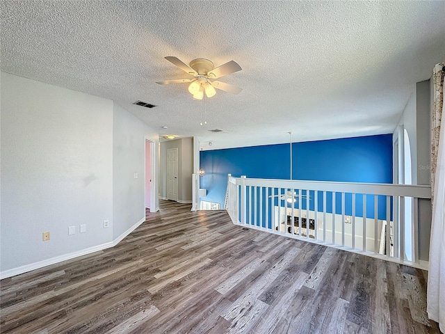 empty room with ceiling fan, a textured ceiling, and hardwood / wood-style flooring