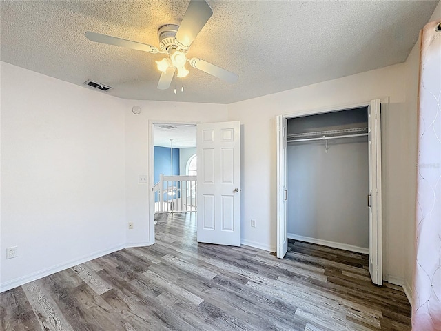 unfurnished bedroom featuring a textured ceiling, a closet, hardwood / wood-style flooring, and ceiling fan