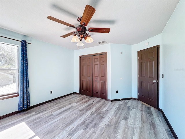 unfurnished bedroom featuring ceiling fan, light wood-type flooring, a textured ceiling, and a closet