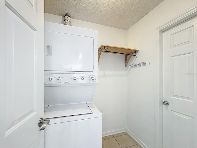 laundry room featuring light tile patterned floors, a textured ceiling, and stacked washer and clothes dryer