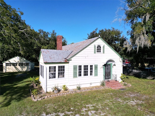 rear view of property with a lawn and an outdoor structure