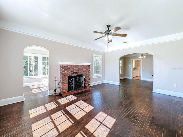 unfurnished living room with crown molding, a fireplace, a healthy amount of sunlight, and dark hardwood / wood-style floors