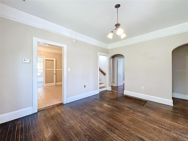 spare room featuring dark wood-type flooring and a notable chandelier