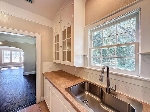 kitchen with backsplash, light hardwood / wood-style flooring, white cabinetry, and sink