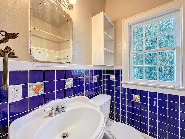 bathroom with toilet, tile walls, and sink