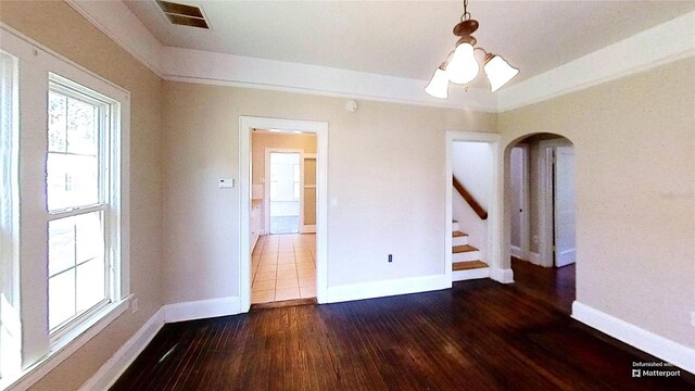 spare room with dark wood-type flooring and a notable chandelier