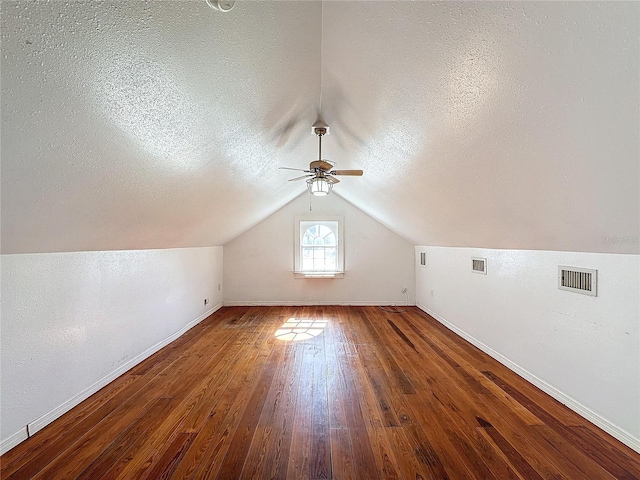 bonus room featuring lofted ceiling, dark hardwood / wood-style flooring, ceiling fan, and a textured ceiling