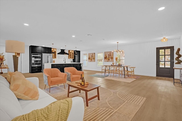 living room with light hardwood / wood-style flooring, a chandelier, and sink