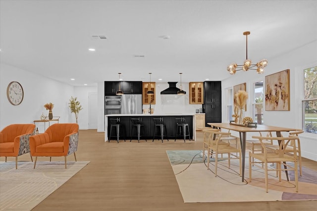 dining area with light hardwood / wood-style flooring and a notable chandelier