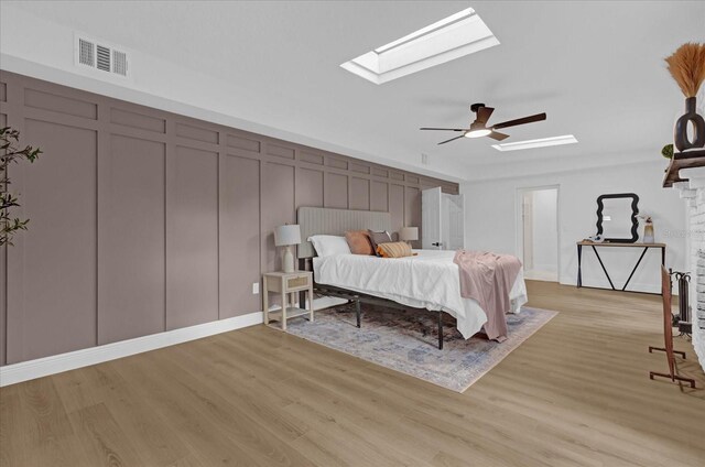 bedroom with ceiling fan, light hardwood / wood-style floors, and a skylight