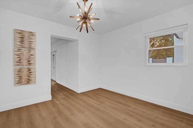 unfurnished room with a chandelier and light wood-type flooring