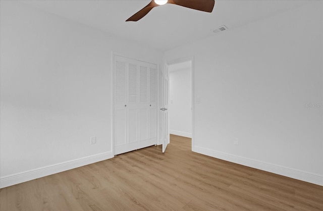 unfurnished bedroom featuring ceiling fan, a closet, and light wood-type flooring