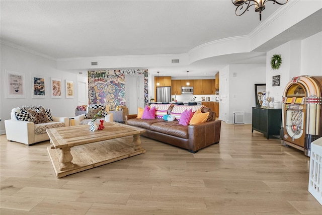 living room featuring a notable chandelier, light hardwood / wood-style floors, and ornamental molding