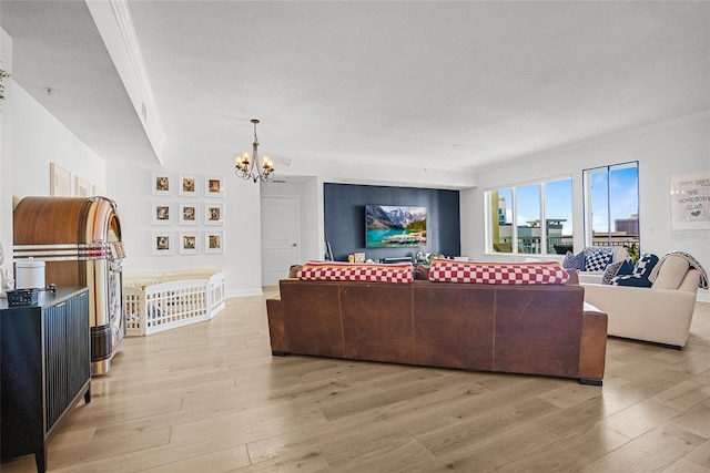 living room with light wood-type flooring, an inviting chandelier, and crown molding