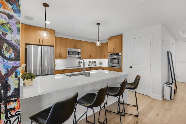 kitchen with appliances with stainless steel finishes, light hardwood / wood-style flooring, hanging light fixtures, and sink