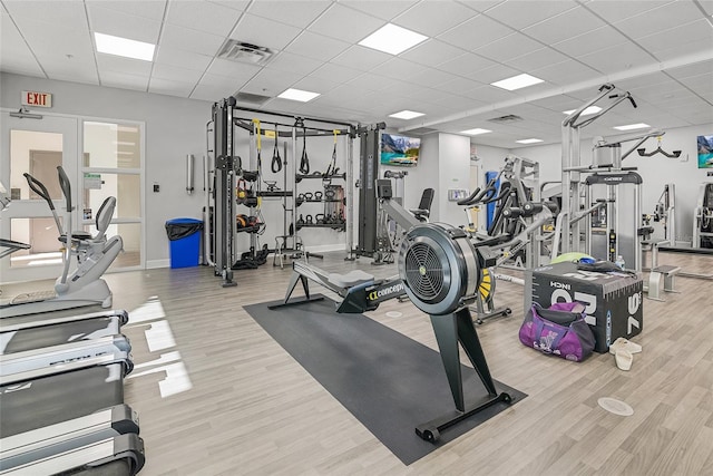 workout area featuring light hardwood / wood-style flooring and a drop ceiling