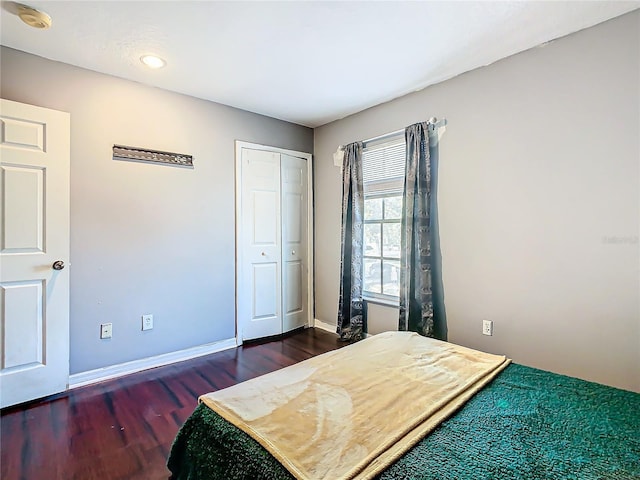 bedroom with dark hardwood / wood-style flooring and a closet